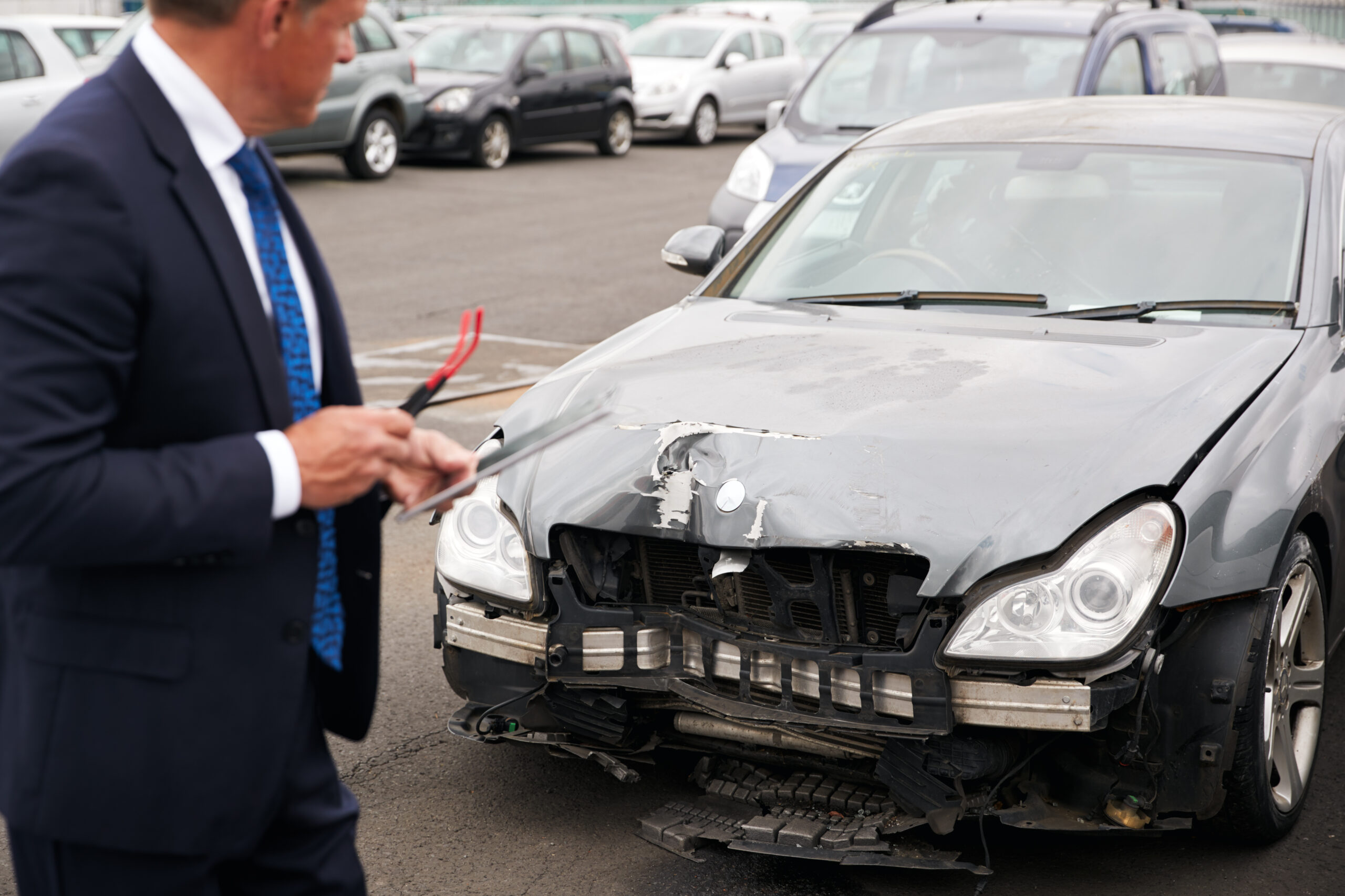 Male Insurance Loss Adjuster With Digital Tablet Inspecting Damage To Car From Motor Accident
